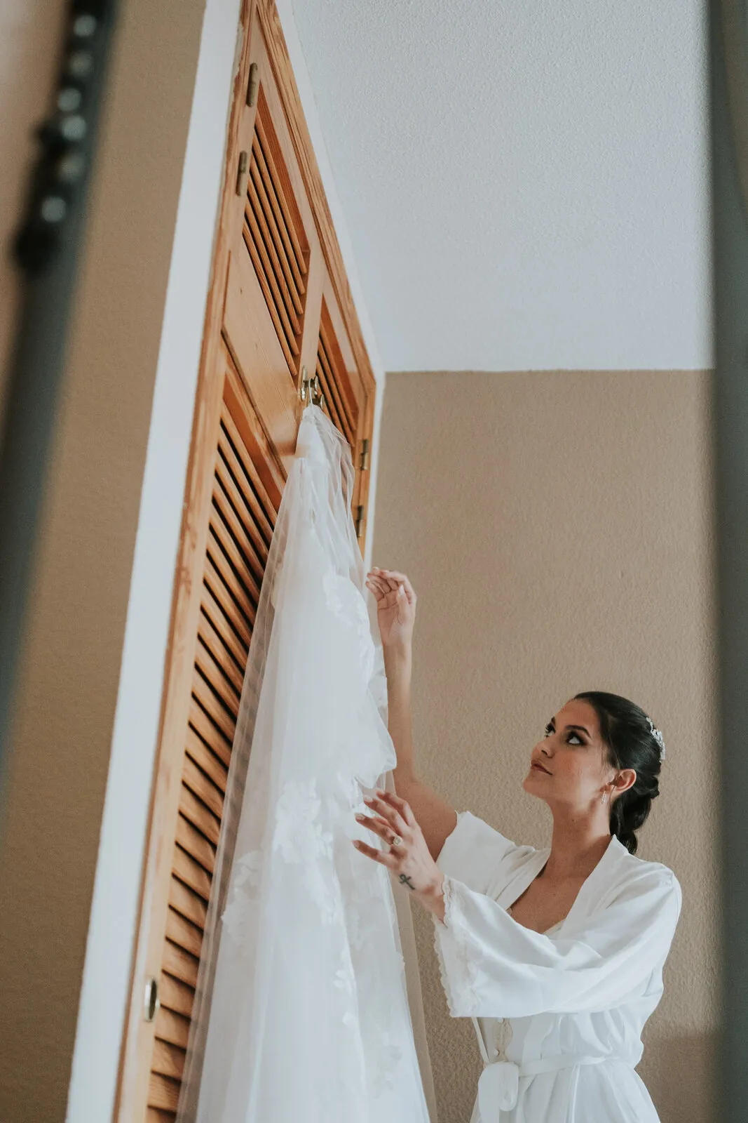 La novia coloca su vestido junto a la ventana con luz de claroscuro