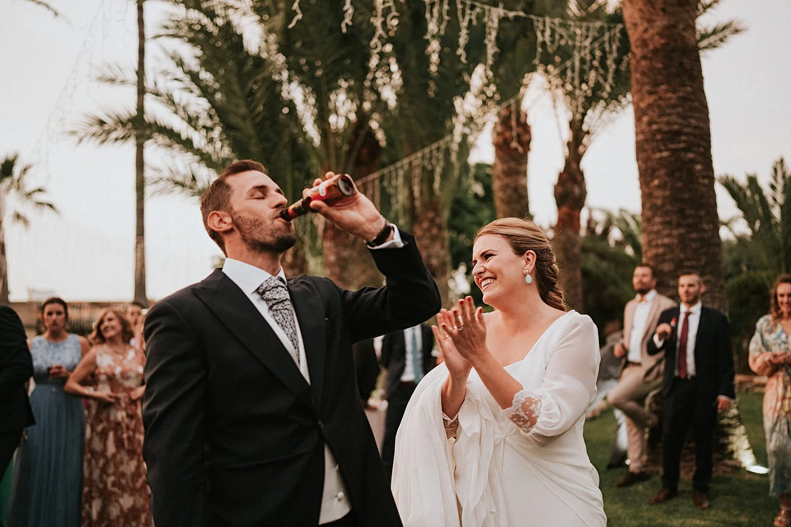 Brindis de los novios entre palmeras al atardecer