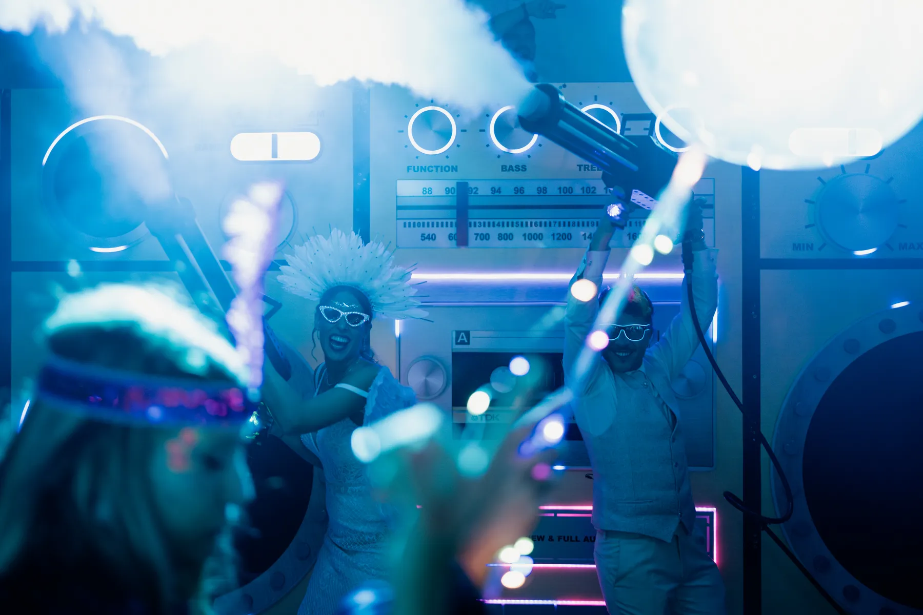 Los novios bailan con gafas de neón entre humo y luces azules