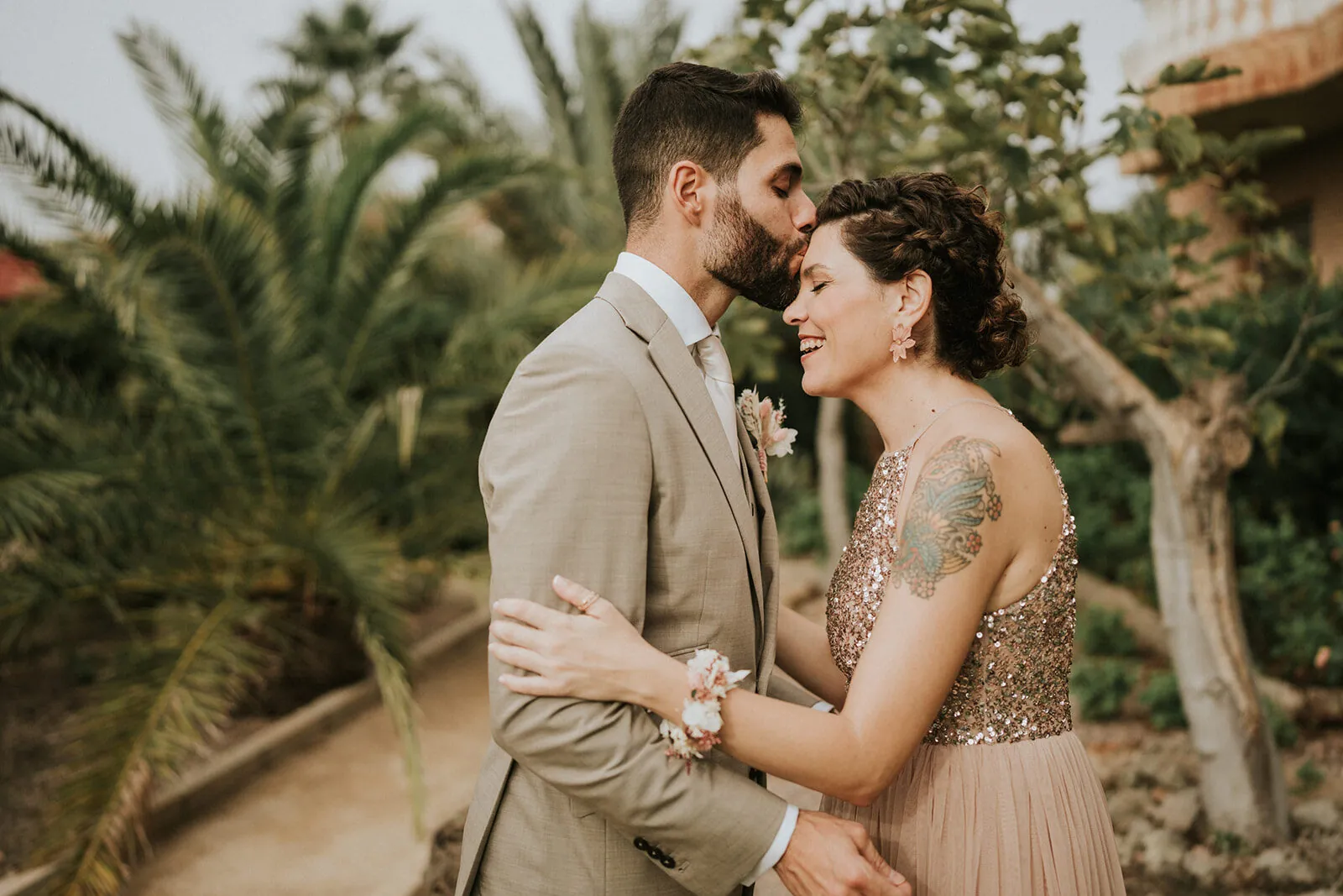 Los novios frente con frente entre palmeras al atardecer en una boda en Murcia